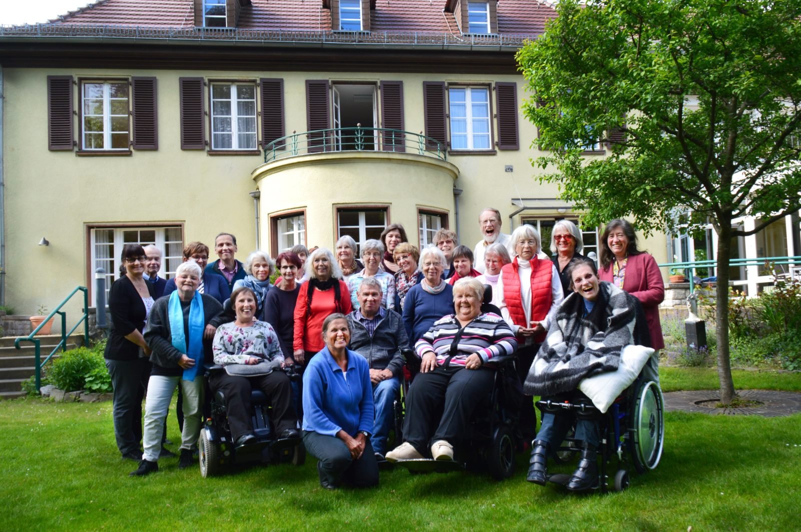 Eine Gruppe posiert vor einer Villa