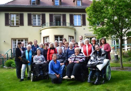 Eine Gruppe posiert vor einer Villa