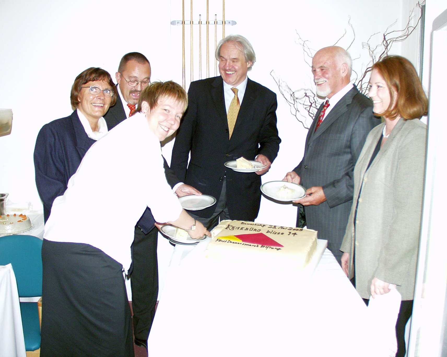 Zur Einweihung des Reisebüros wird Torte serviert. Beim Anschneiden herrscht bereits gute Laune.