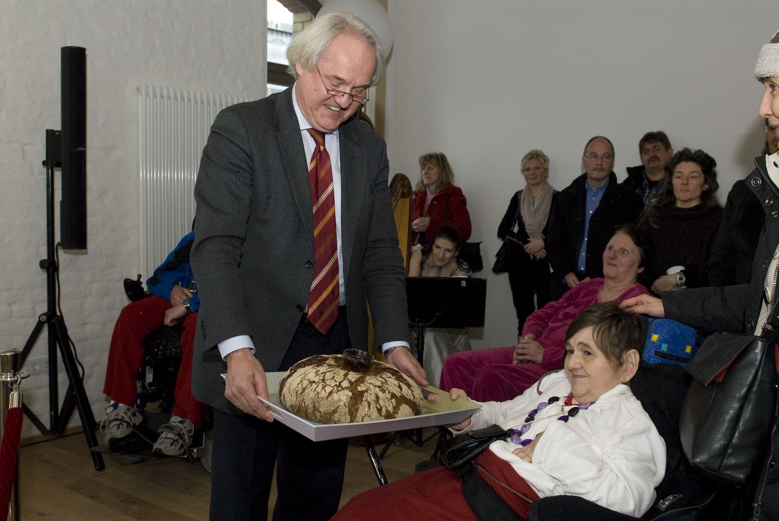Wolfgang Schrödter überreicht einer Bewohnerin des WmI Pankow das symbolische Brot und Salz.