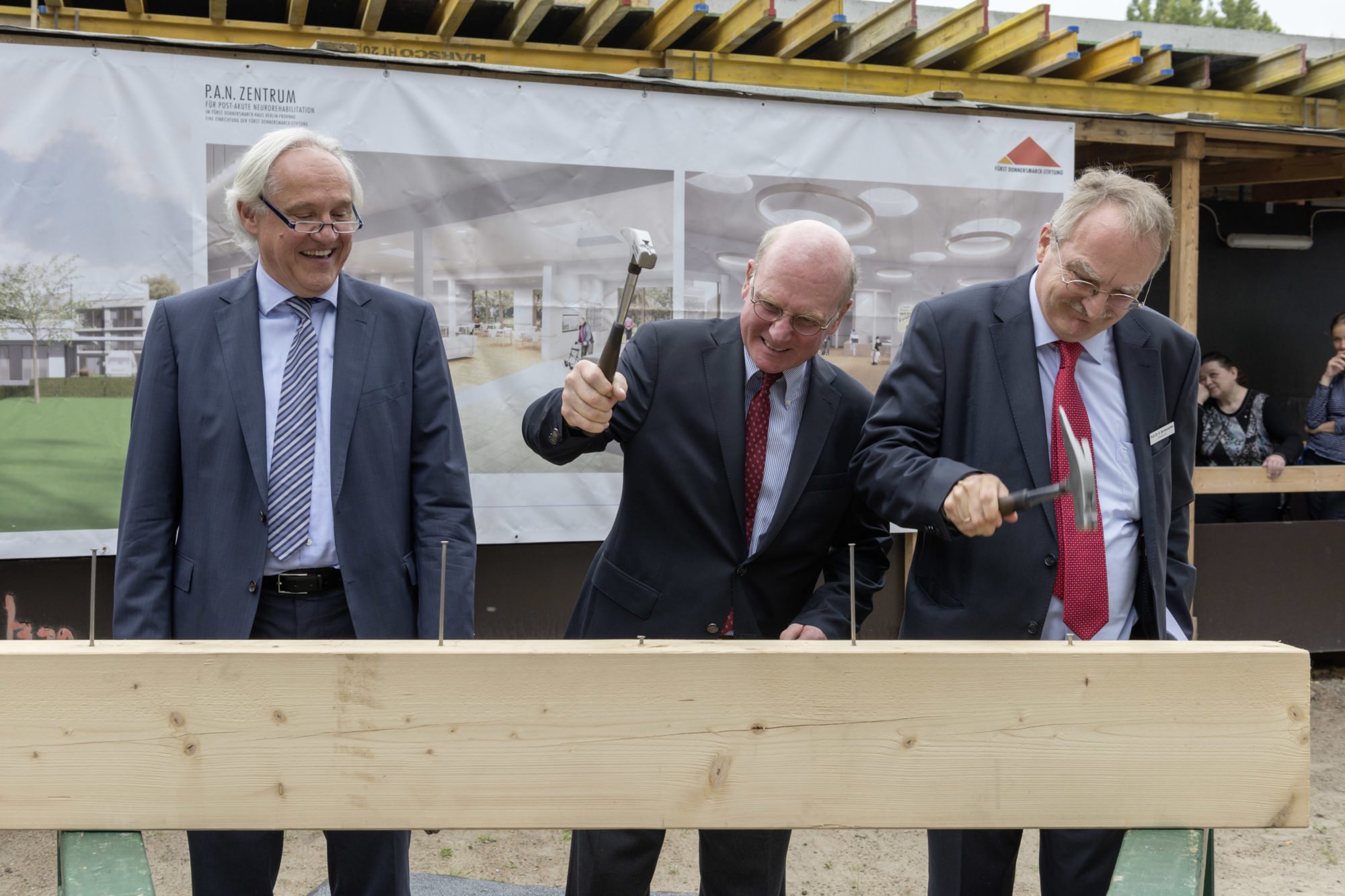 Die ersten Nägel werden in den Balken geschlagen und Wolfgang Schrödter schaut vergnügt zu.