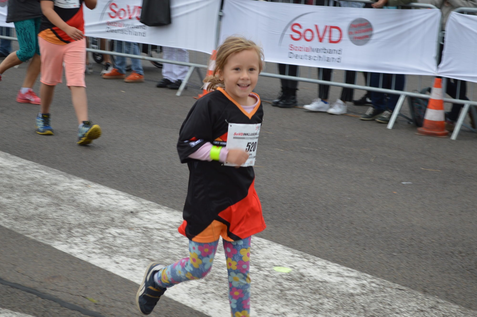 Mädchen beim Bambini-Lauf lächelt in die Kamera.