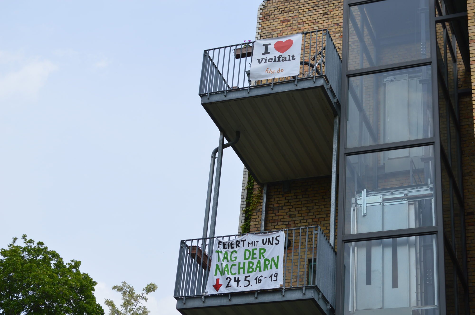 Die Balkons in den oberen Etagen geschmückt mit Bannern: Tag der Nachbarn 2019 und I love Vielfalt.