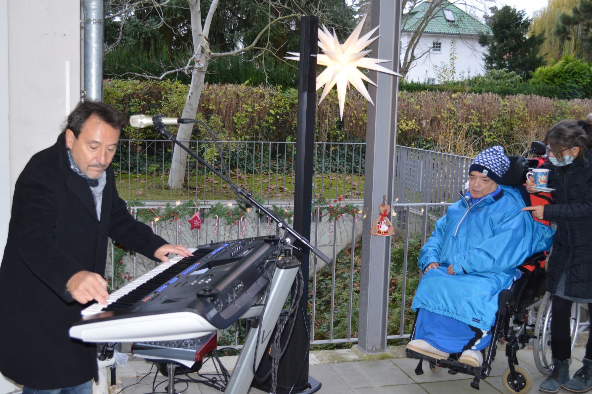 Ein Musiker mit Keyboard spielt vor dem Haus. 
