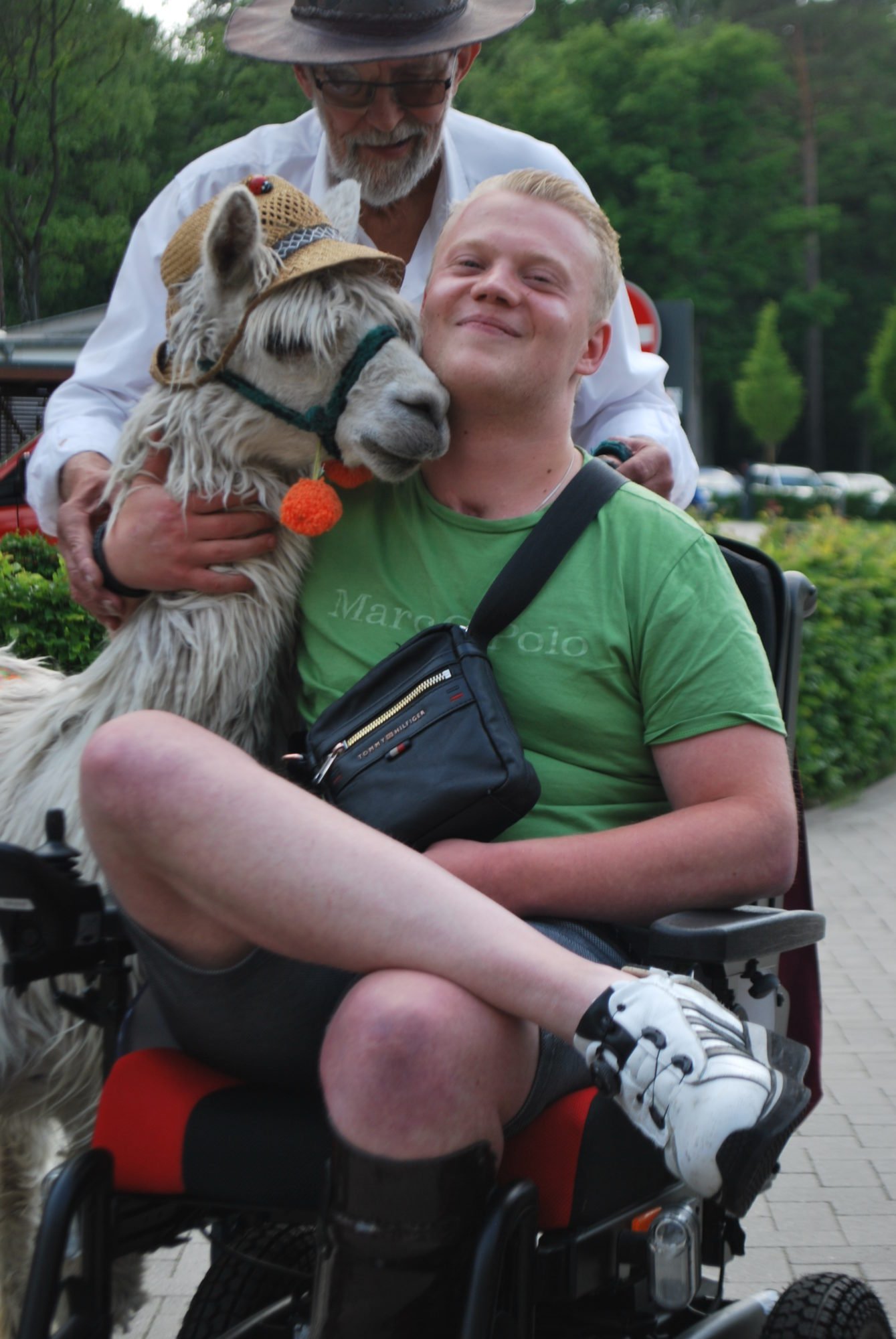 Ein Rehabilitand im Rollstuhl lässt sich mit dem Alpaka fotografieren.