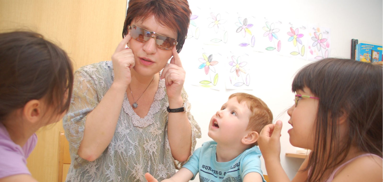 Silja Korn und mehrere Kita-Kinder sitzen zusammen. Die Kinder schauen ihre Erzieherin an.
