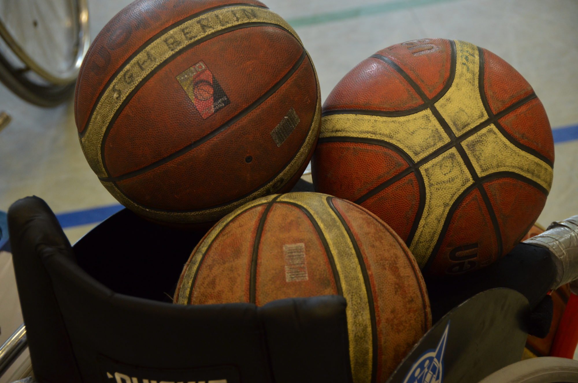 Drei Basketbälle auf einem Rollstuhl.