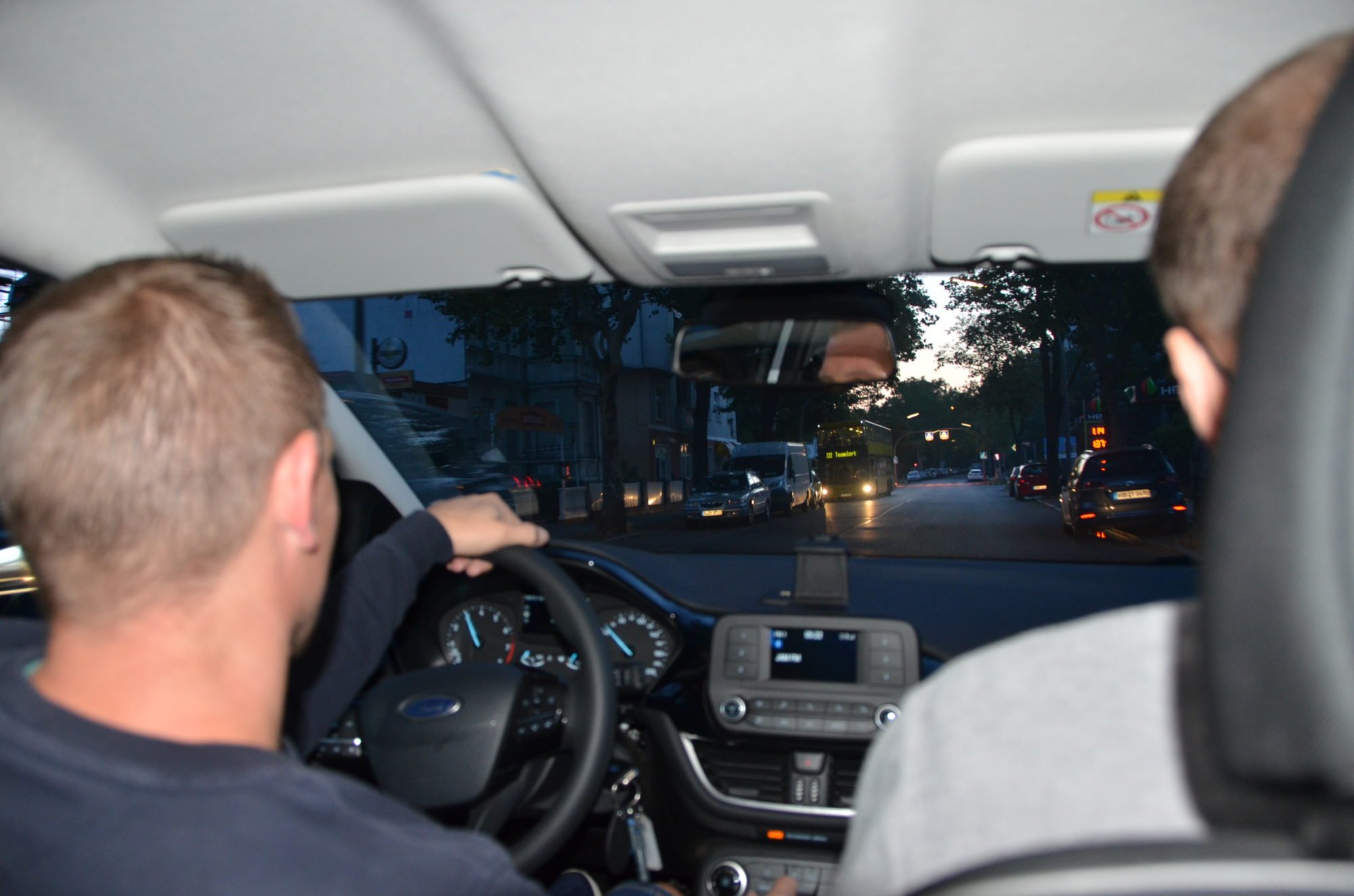 Vom Rücksitz des Autos über die Schultern von Marco Noack und Dr. Sebastian Weinert fotografiert. Es ist noch dunkel, auf der Straße fährt sonst nur ein Bus.