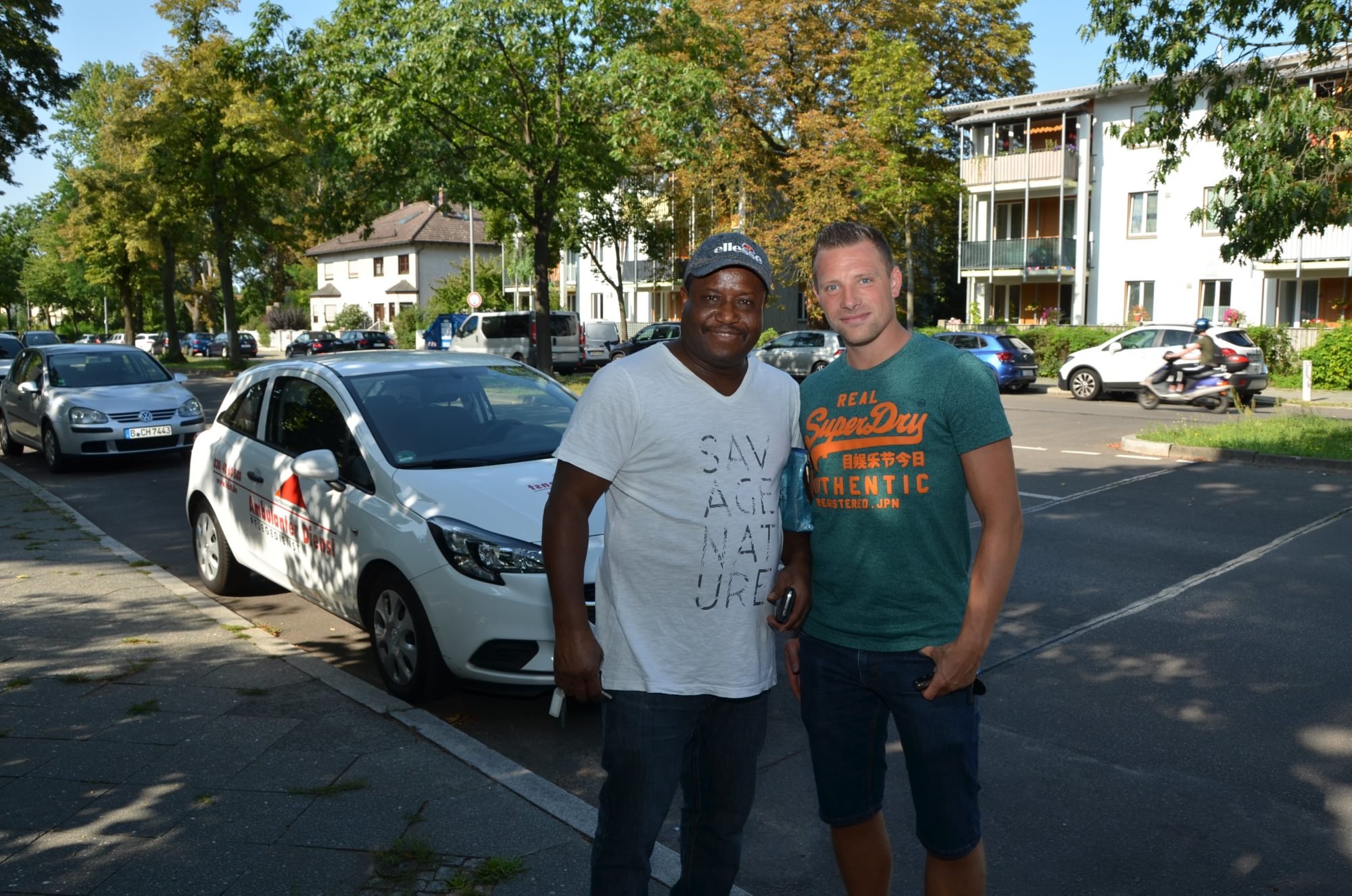 Marco und sein Kollege John posieren auf der Straße gemeinsam für ein Foto.