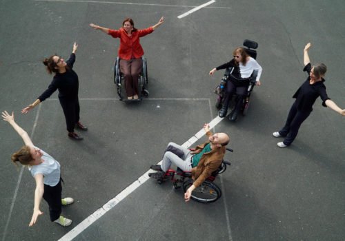 Stehende und sitzende Menschen in einem Kreis auf Asphalt