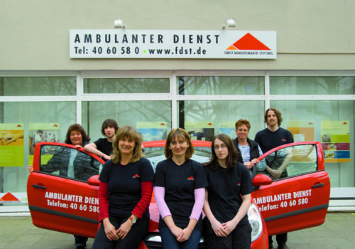 Gruppenfoto vor einem Auto und den Büros des Ambulanten Dienstes.