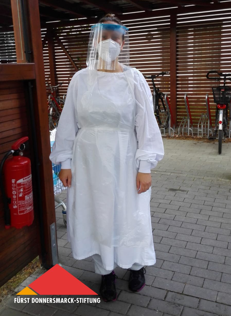 Yvonne Grabow trägt einen Schutzkittel, eine Mund-Nasen-Maske und ein Schutzvisier.
