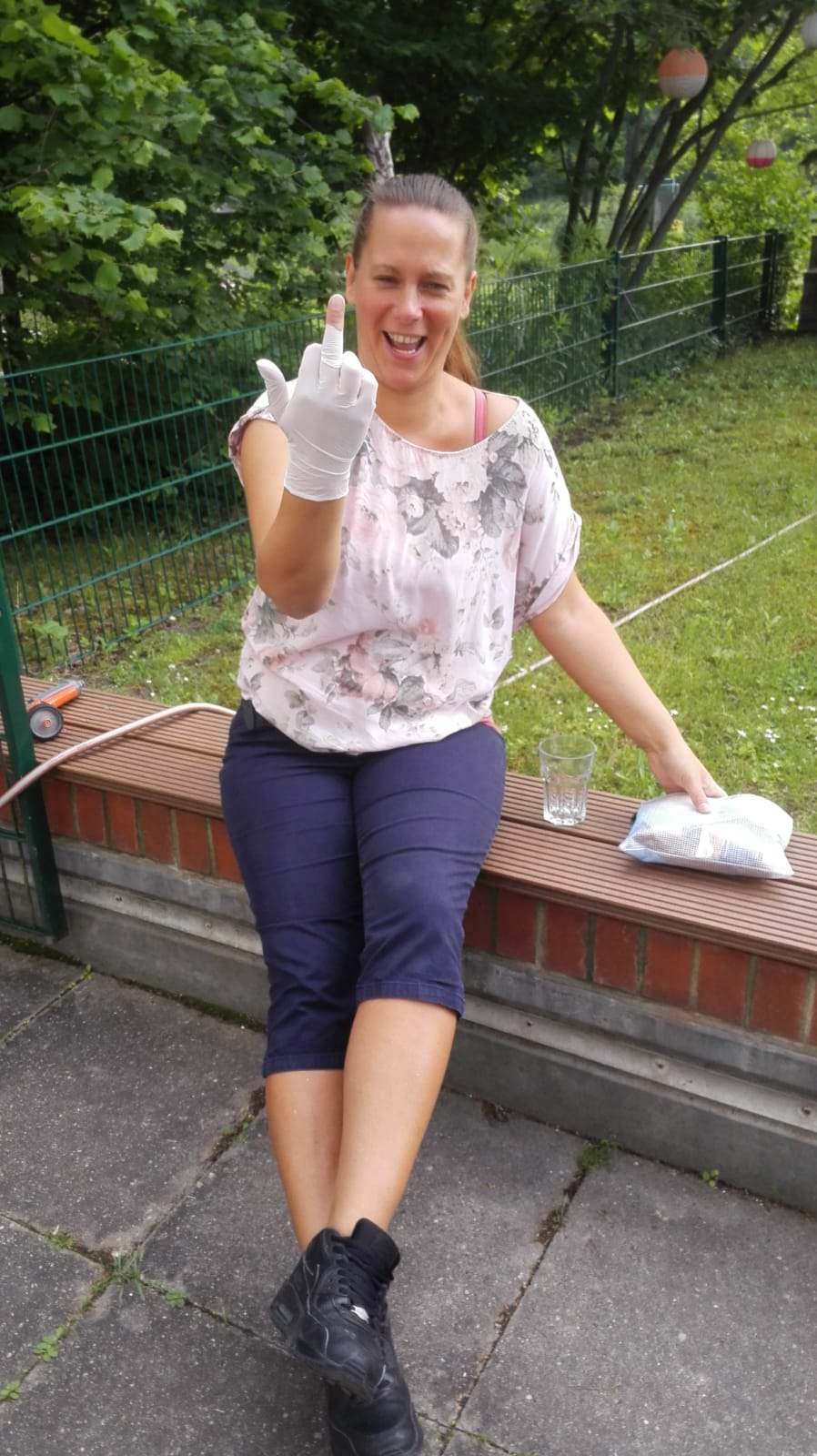 Yvonne Grabow lacht in die Kamera. Sie hat einen Gummihandschuh an, der am Mittelfinger gerissen ist. Sie streckt den Mittelfinger aus.