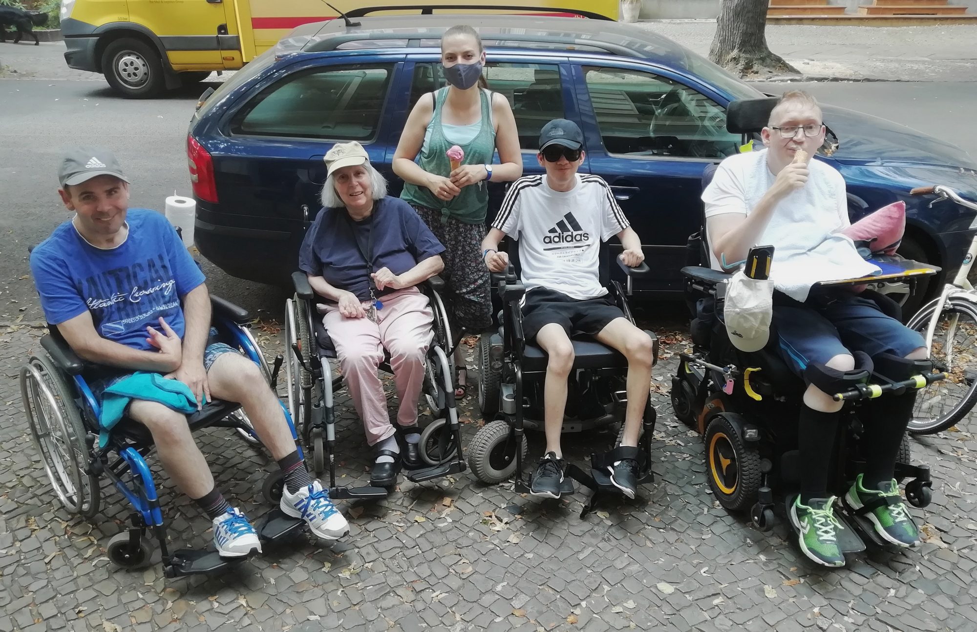 Larissa Bögel unterwegs mit drei Klienten und einer Klientin, die alle im Rollstuhl unterwegs sind.