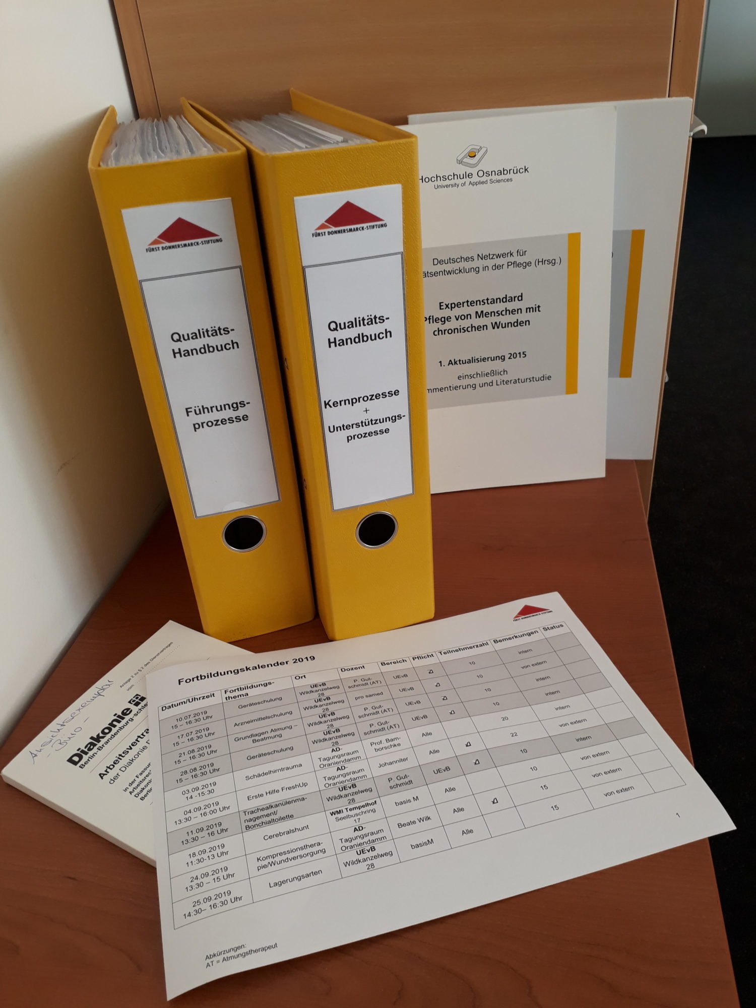 Ein Ordner, gedruckte Expertenstandards und eine Exceltabelle sind zu sehen