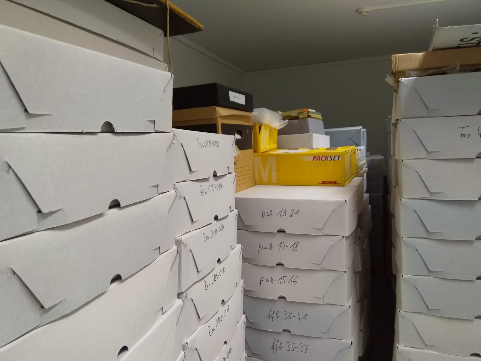 Im Bild sind stapelweise Archivkisten zu sehen.
