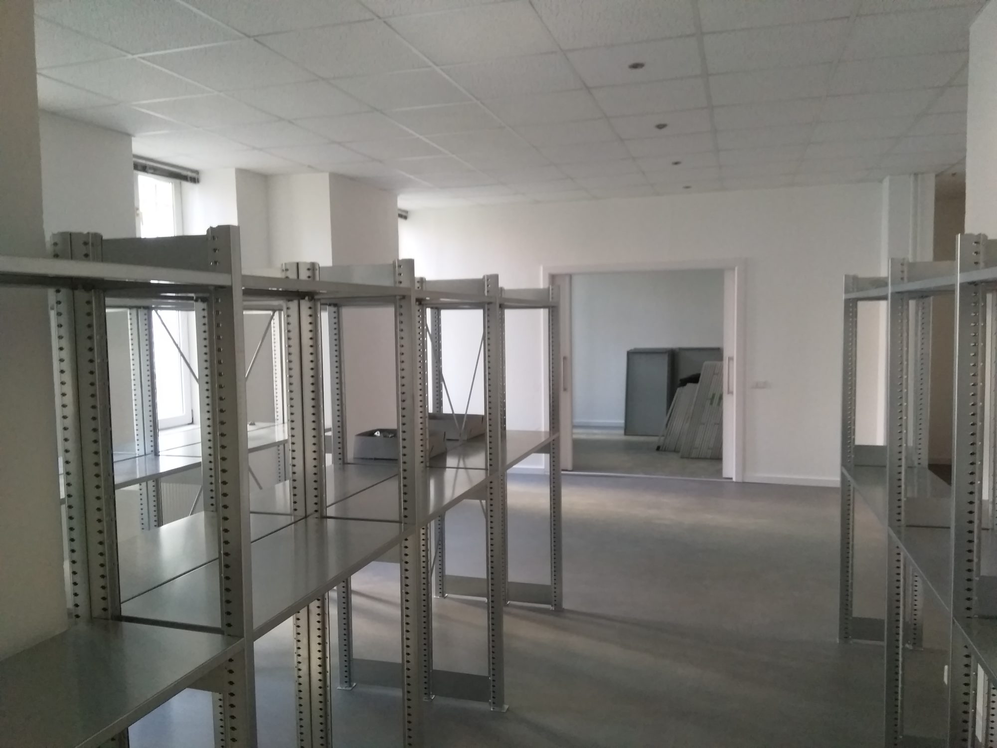 Leere Metallregale und weiße Wände - die neuen Archivräumlichkeiten.