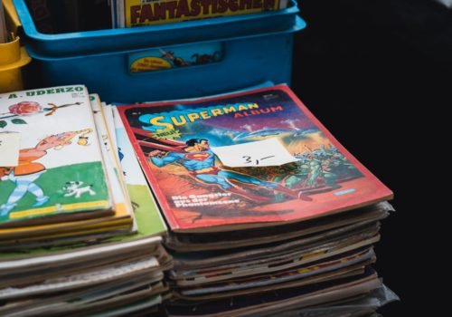 Alte Comichefte gestapelt und dahinter Kisten mit mehr Heften.