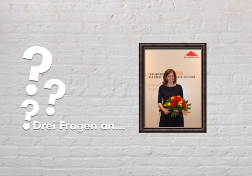 Zu sehen ist ein Bild von Sonja Suntrup-Krüger auf der Verleihung des Forschungspreis 2018 sowie drei Fragezeichen und der Titel "Drei Fragen an"