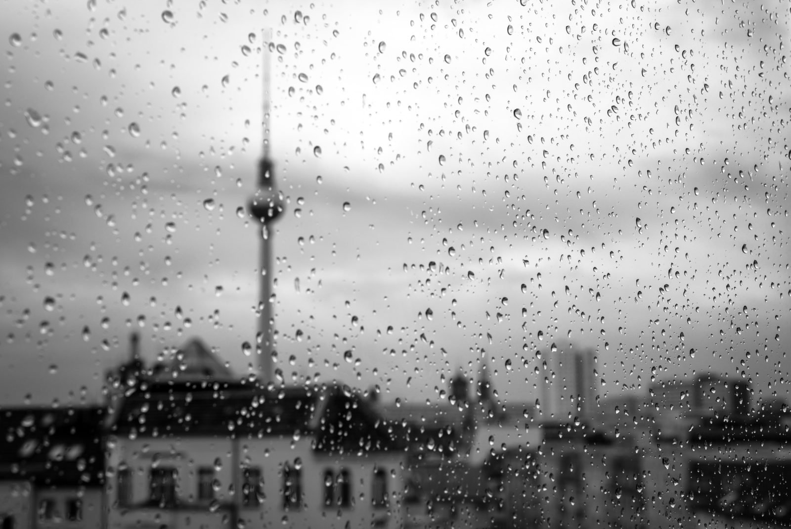Regnerisches Wetter - Regentropfen laufen eine Fensterscheibe hinunter. Im Hintergrund ist der Berliner Fernsehturm zu sehen.