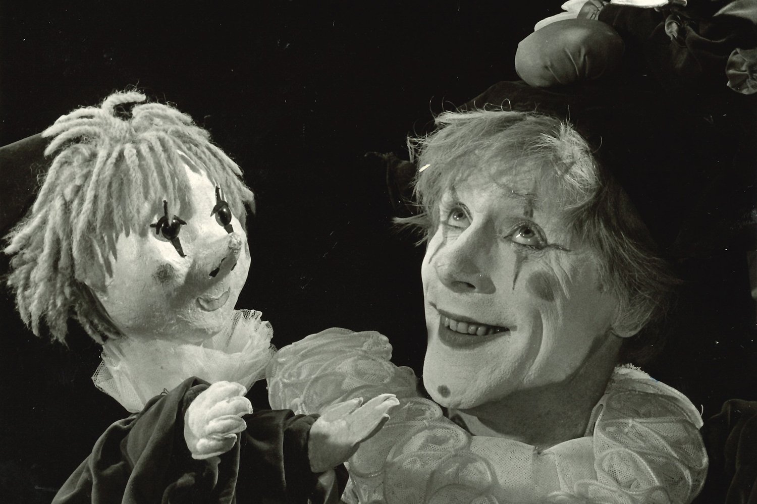 Ein geschminkter Clown mit einer Clown-Handpuppe. Scan eines Schwarzweißfotos.