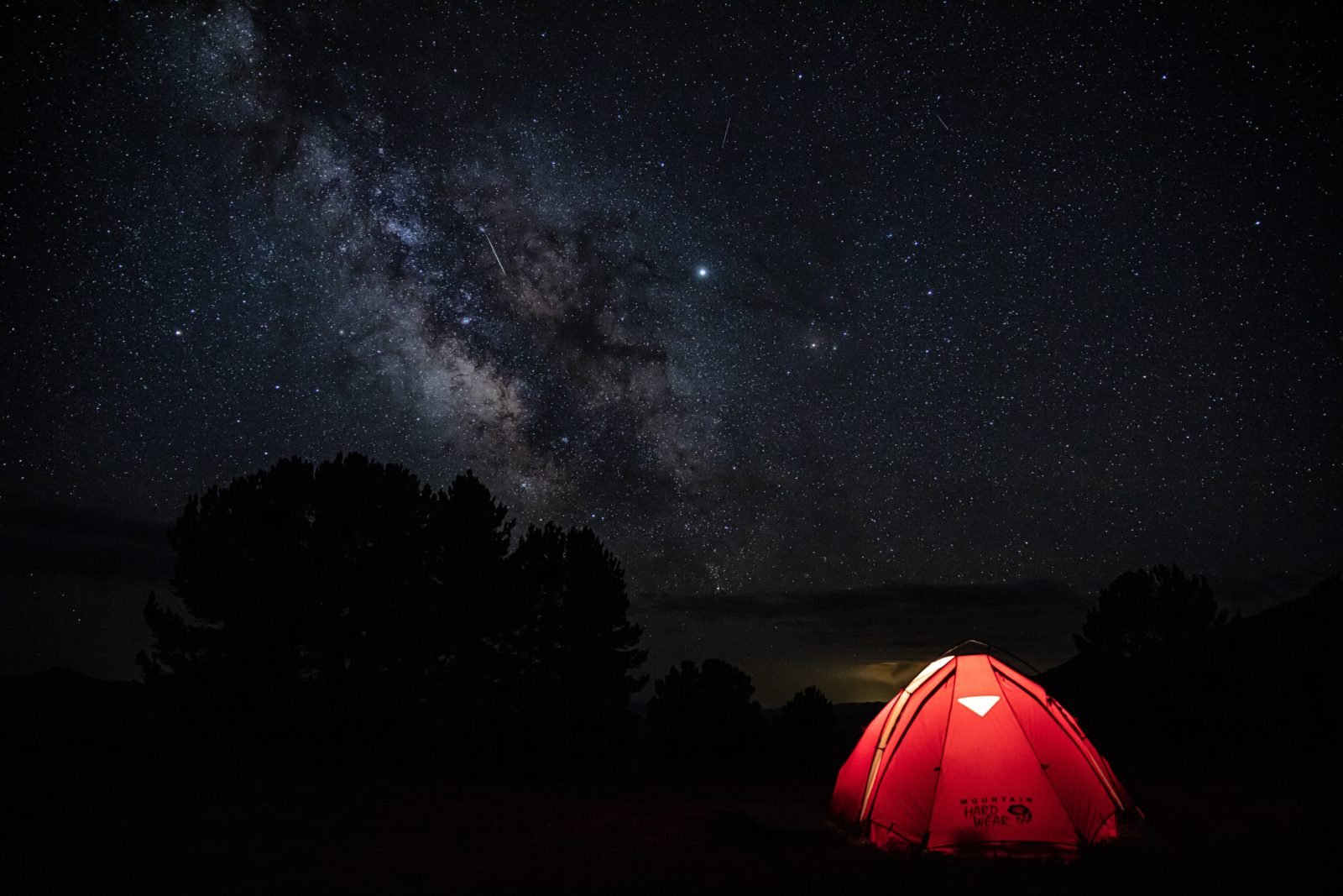 Traumvorstellung für Camping mit Rollstuhl: Ein rotes Zelt auf einer Waldlichtung und klarer Sternenhimmel.