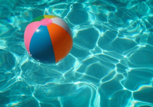 Ein bunter mit Luft gefüllter Plastikball schwimmt auf Wasser.