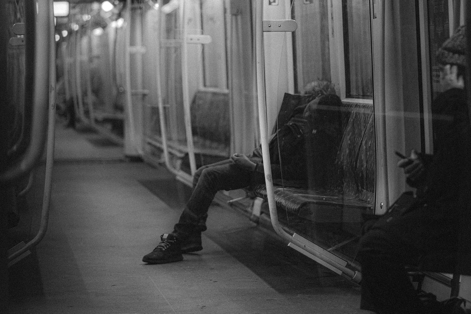 Schwarz-Weiß Foto aus der Berliner U-Bahn Ein Mann schläft auf der Sitzbank.